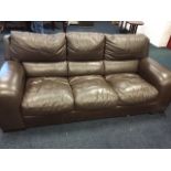 A large leather upholstered three-seater sofa with panelled cushions, raised on block feet. (86in