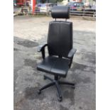 A modern adjustable upholstered office armchair with headrest above shaped padded back, the seat