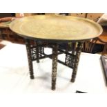 An eastern brass tray-top coffee table, the tray with star medallion framed by floral scrolled