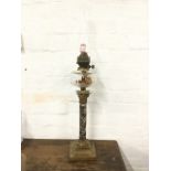 A Victorian oil lamp with oval glass chimney above a facet cut bun shaped reservoir, supported on