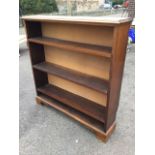 A mahogany open bookcase with moulded top above adjustable shelves, raised on bracket feet. (42in