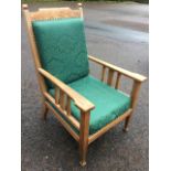 An arts & crafts style armchair upholstered in green damask, the back panel with brass studding