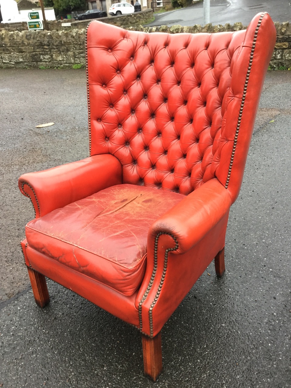 A Georgian style leather button upholstered wingback armchair, with brass studding and loose