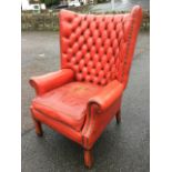 A Georgian style leather button upholstered wingback armchair, with brass studding and loose