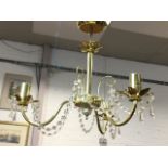 A contemporary hanging brass chandelier with three scrolled branches on column with leaf mounts, the