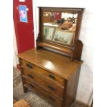 An art nouveau oak dressing table with bevelled mirror above a shelf, the chest with rectangular