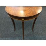 A small 'D' shaped mahogany hall table, the crossbanded top on tapering sabre legs, the frieze