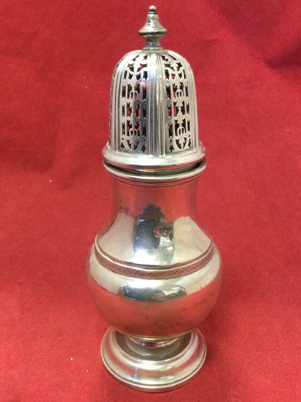 A Georgian style hallmarked silver caster, the pierced hexagonal domed cover with turned finial