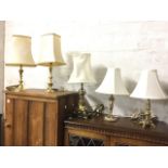 Five brass tablelamps mounted with cream fabric shades - fluted, floral embossed, baluster style,