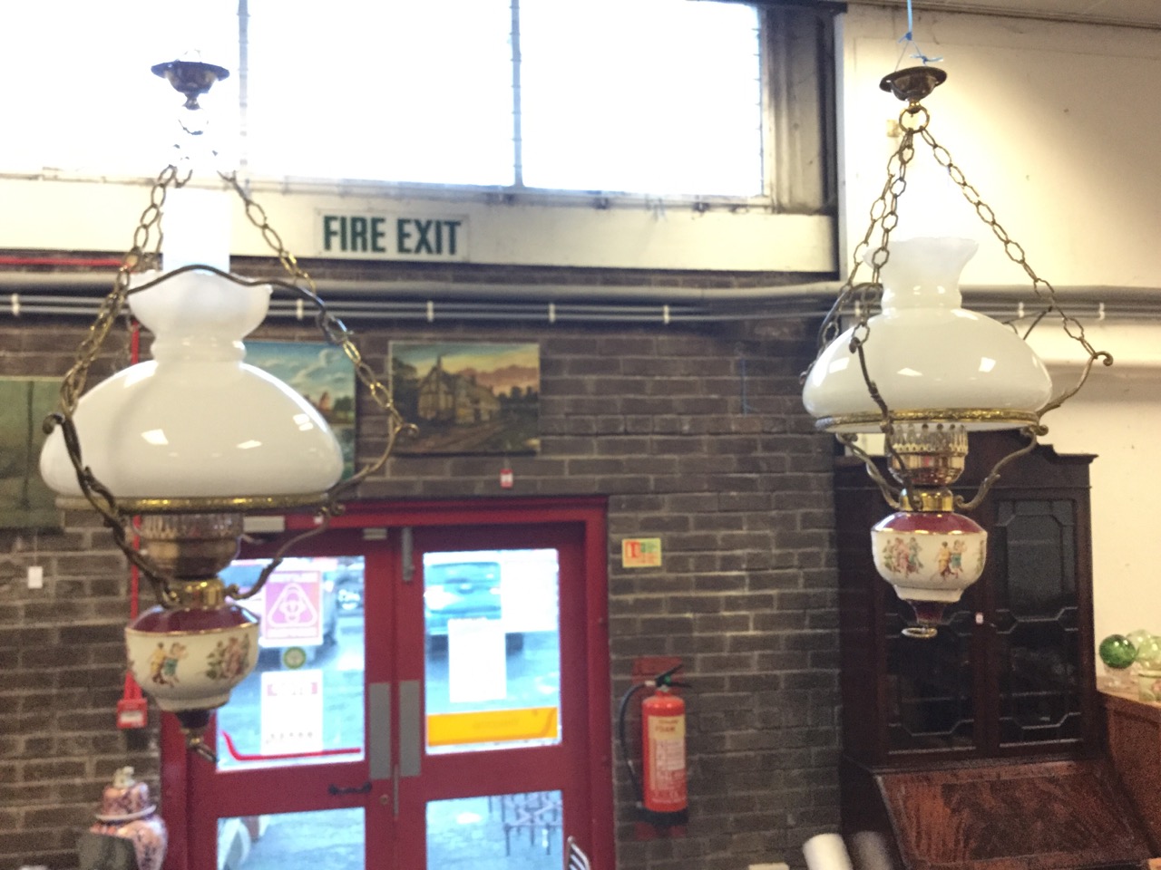 A pair of Victorian style hanging oil lamps, the electric wired lights having ceramic reservoirs