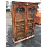 A glazed mahogany bookcase cabinet with moulded top above arched leaded glass doors enclosing