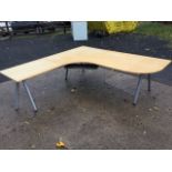 A large modern corner office desk with wide rounded work surface having shelf below, raised on