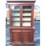 A Victorian mahogany bookcase cabinet with moulded ogee cornice above rounded glazed doors enclosing