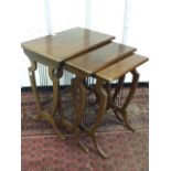 A nest of three mahogany tables with rectangular moulded tops on shield shaped lyre supports with