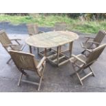 A teak garden suite, the oval slatted table with drop leaves on rectangular frame, the six folding