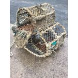Three lobster pots with hooped metal frames, having drop down ends and each with three entry points.