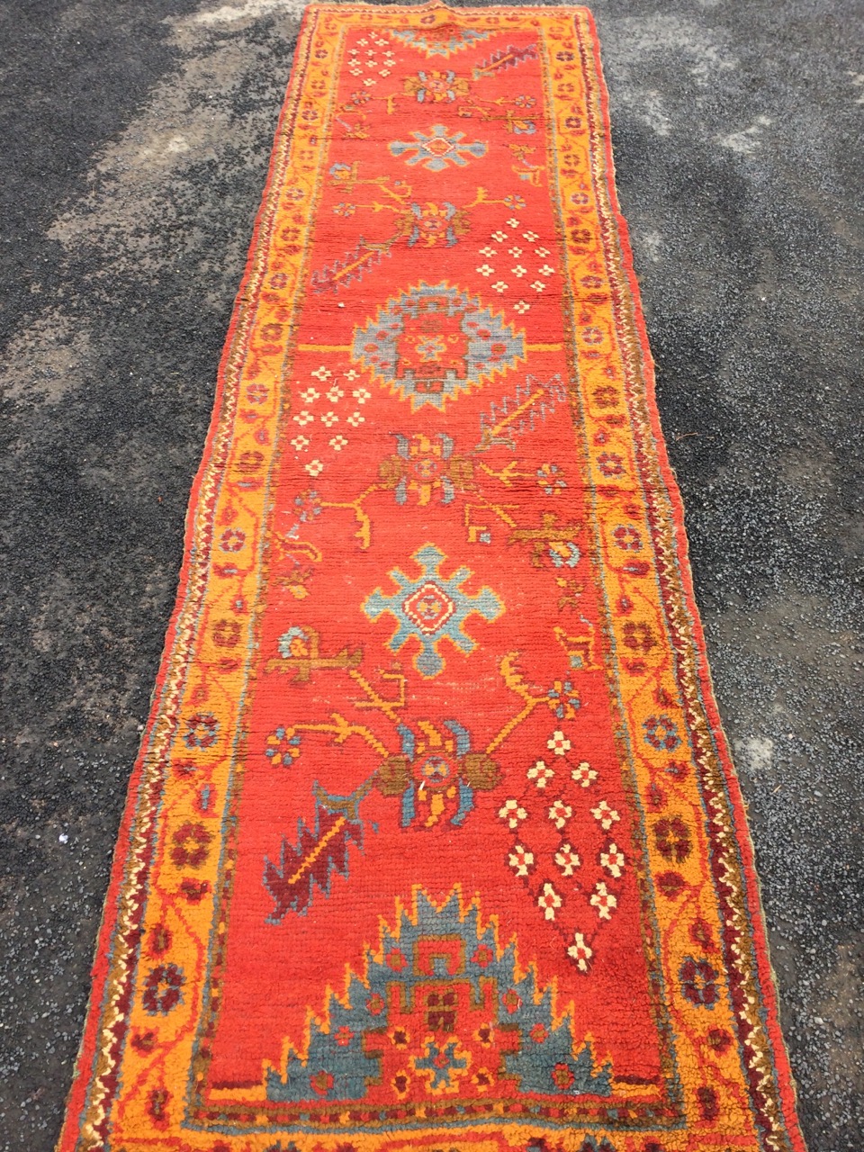 A Turkey runner, the red field woven with serrated, star & floral motifs framed by orange border