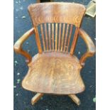 An oak office chair with deep curved back rail on slats, having rounded arms on shaped supports, the