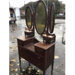 An Edwardian oak dressing table with three oval bevelled mirrors above two small drawers, the