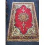 A Persian sarouk style rug woven with floral medallion in red field having lotus style spandrels