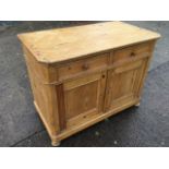 A European pine cabinet with canted corners, having two panelled drawers above panelled cupboards,