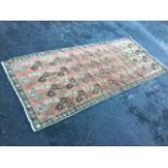 An oriental rug woven with floral designs in pink field framed by brown border with leaf and