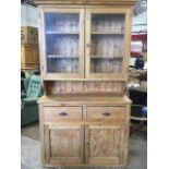 A Victorian pine dresser, with moulded cornice above glazed doors enclosing shelves, the base with