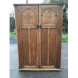 A carved oak wardrobe with moulded cornice above chamfered panelled doors carved with floral diamond