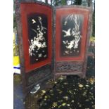 A nineteenth century Japanese two-fold screen having wide lacquer panels inlaid with bone and