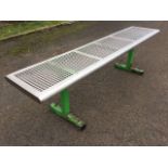 A stainless steel bench with rectangular grill seat on square metal supports. (70.75in)