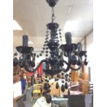 A contemporary black chandelier, with column suspended from ceiling rose having honeycomb moulded