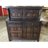 A Priory oak court cupboard, the top with quartered panelled doors beneath an arch fluted frieze