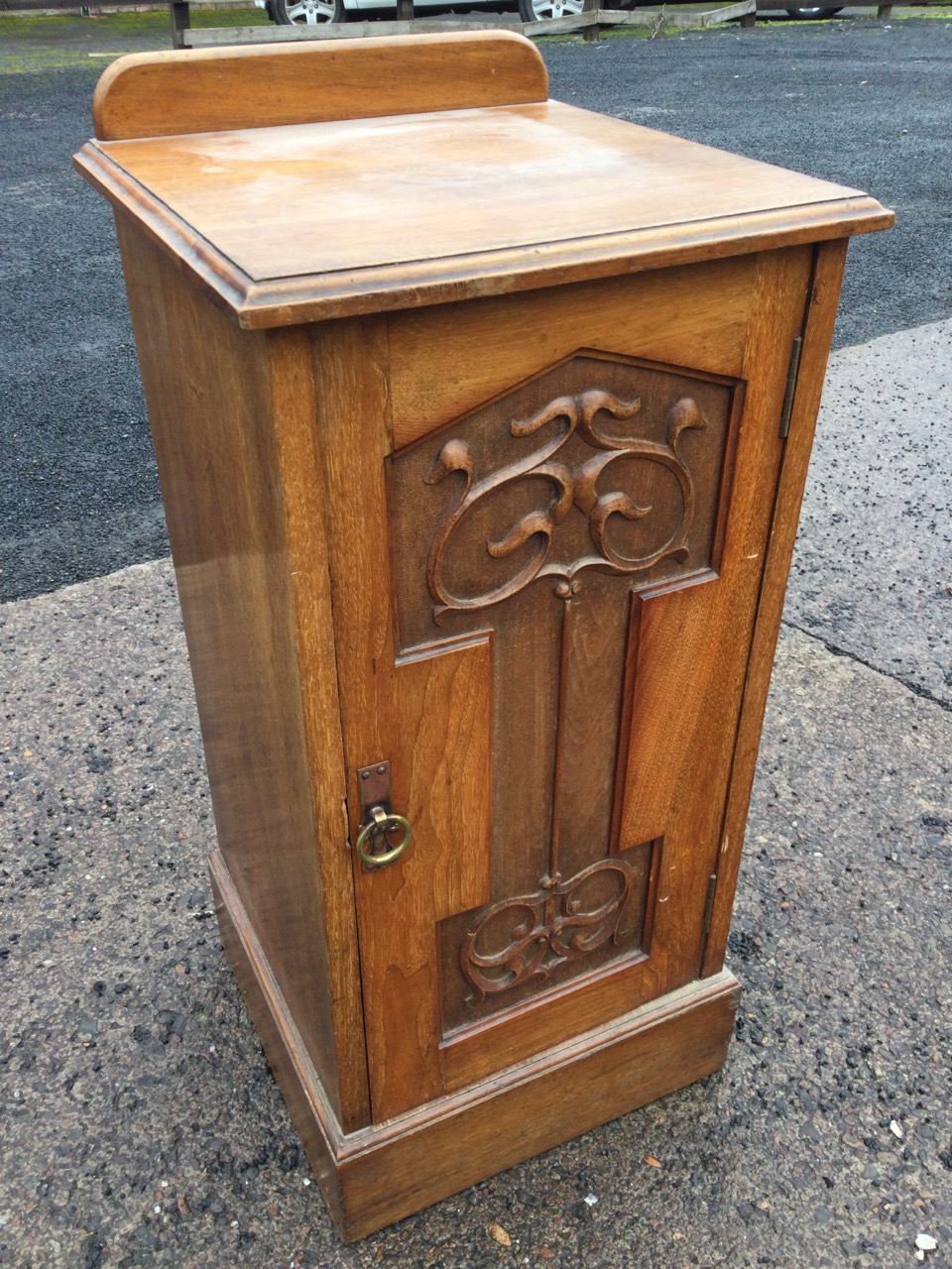 An art nouveau mahogany pot cupboard with moulded top above a scroll carved panelled door mounted