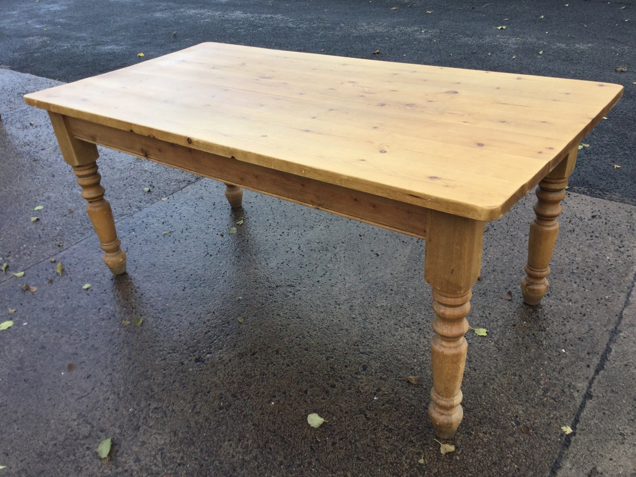 A pine kitchen table, the rectangular thick plank top on turned legs. (70.5in x 35.5in x 30.75in)