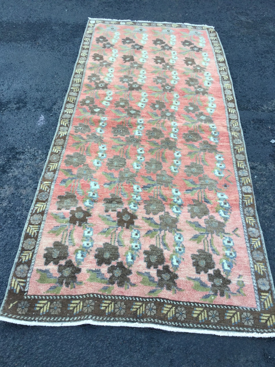 An oriental rug woven with floral designs in pink field framed by brown border with leaf and - Image 3 of 3