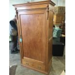 A Victorian pitch pine wardrobe with moulded cornice above a wide panelled door enclosing hanging