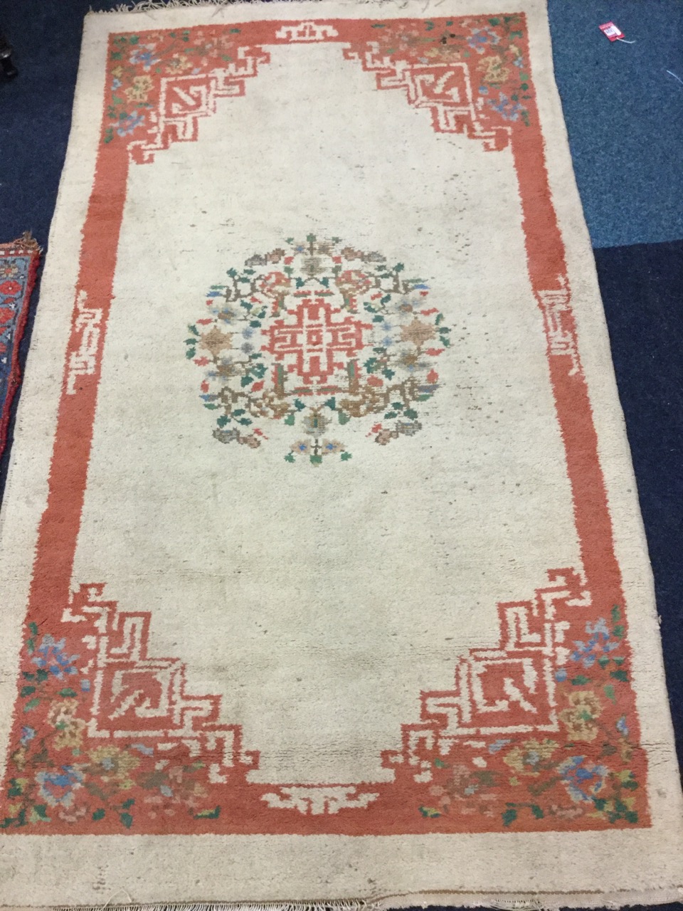 A Chinese style wool rug woven with circular floral medallion on fawn ground, the salmon pink border