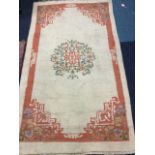 A Chinese style wool rug woven with circular floral medallion on fawn ground, the salmon pink border