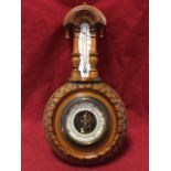 A Victorian walnut cased aneroid barometer with circular dial under brass bezel in leaf chisel