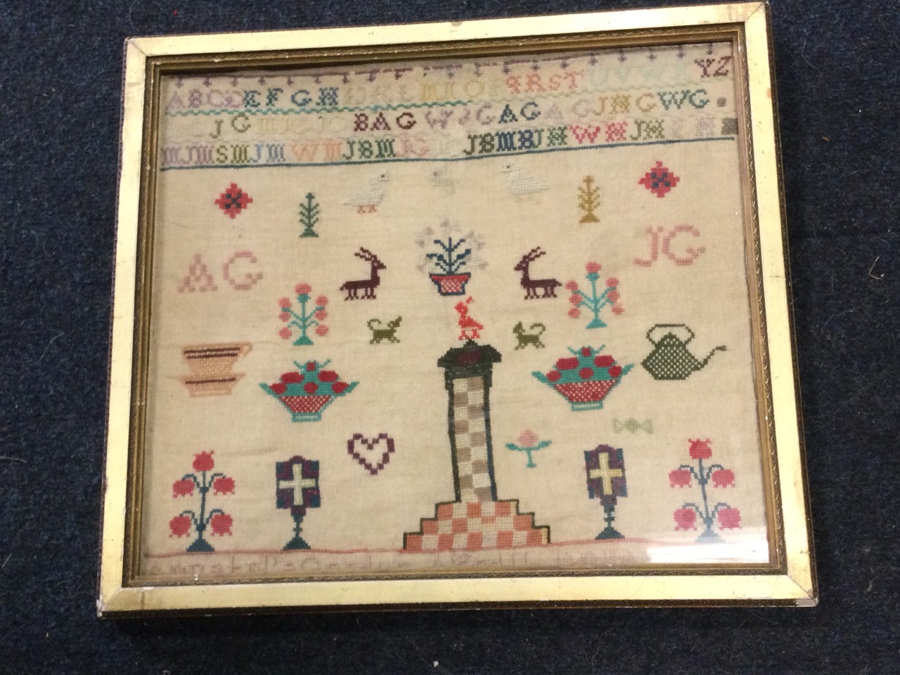 A gilt framed Victorian sampler dated 1863, with alphabet above panel of flowers, deer, vases,