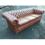 A button upholstered leather three-seater chesterfield sofa, the padded back with studded arms above