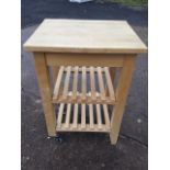 A beech kitchen trolley stand with rectangular top above two slatted shelves, raised on square