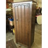 An oak wardrobe with moulded cornice above a wide panelled door having applied mouldings and blind