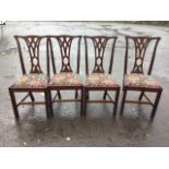 A set of four mahogany Chippendale style dining chairs with pierced splats above floral