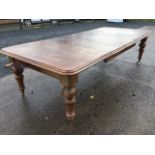 A large Victorian mahogany wind-out dining table, the moulded rounded top with three leaves,