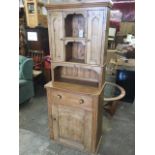 A small pine dresser with moulded cornice above twin open compartments flanked by panelled doors,