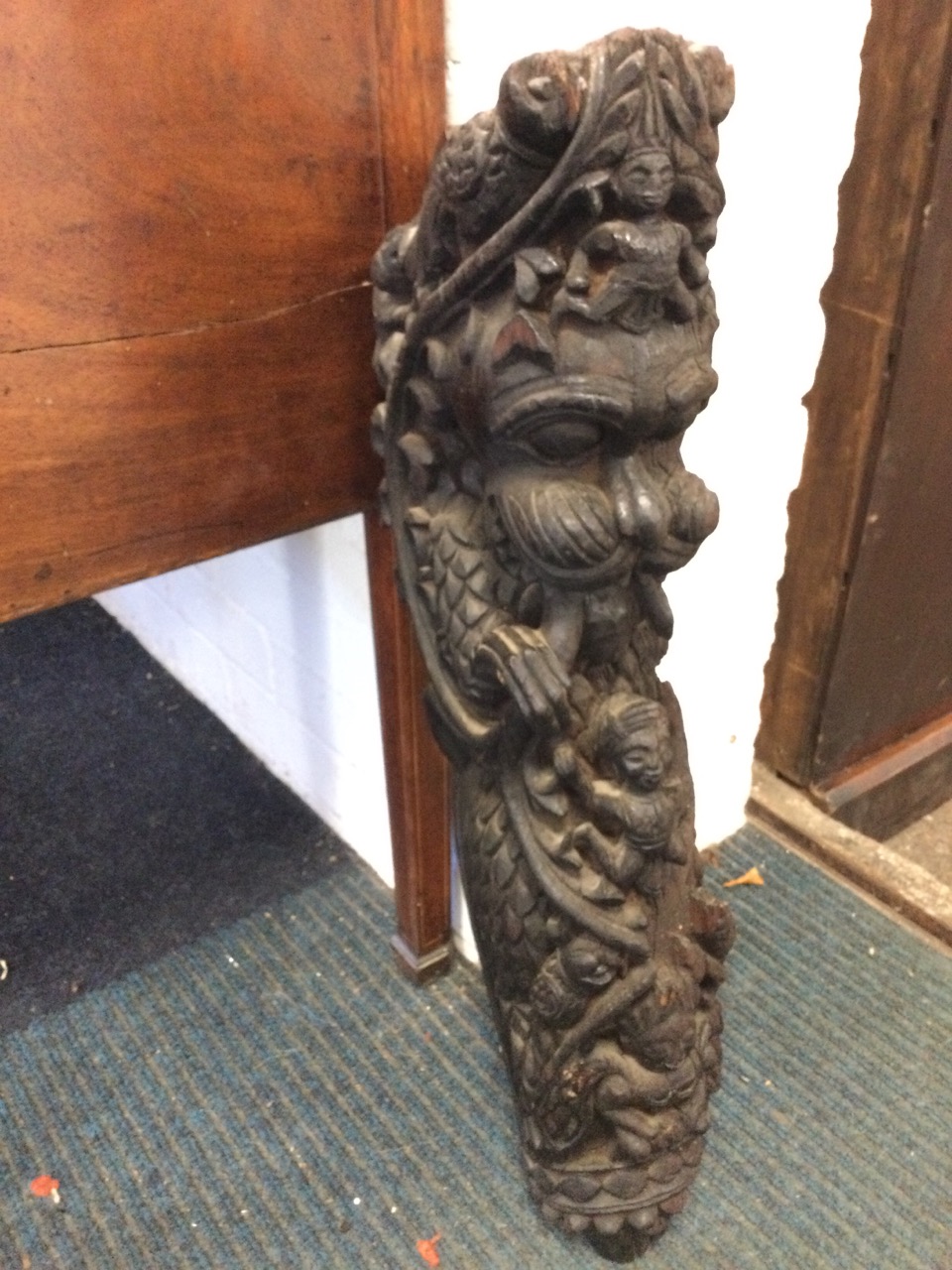 An antique eastern carving from a building, the stylised clawed dragon with foliage, encrusted