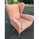 A hessian upholstered 60s wing back armchair with padded back and arms above a loose cushion and