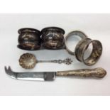 Four silver napkin rings, silver handled cheese knife and a white metal caddy spoon