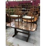 An Ercol extending dining table and two matching elbow chairs with loose cushions